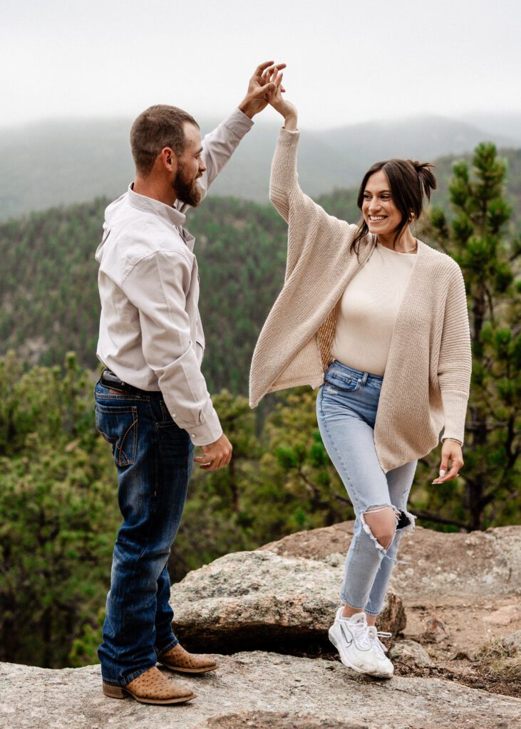 newly engaged couple dancing on the side of mountain during their proposal in colorado