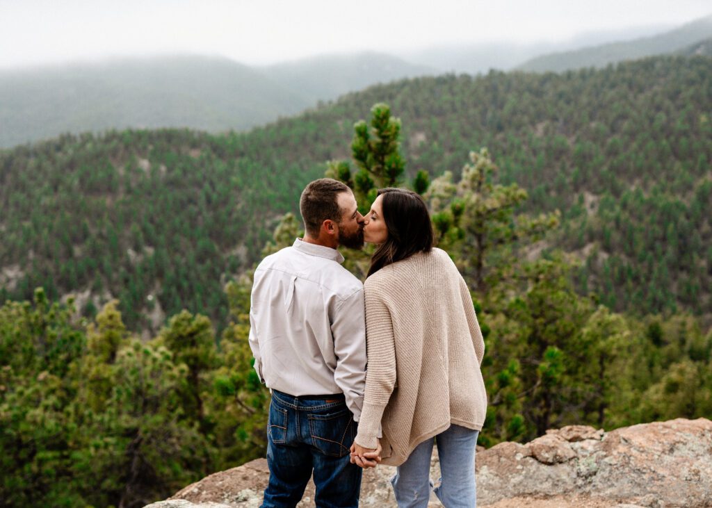 couple facing away from the camera towards the mountains kissing during their proposal in colorado