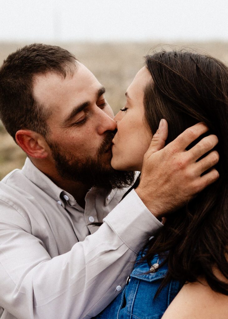 fiance kissing his girlfriend while stroking her hair out of her face during their proposal in colorado