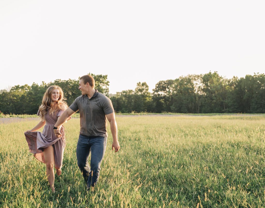 couple holding hands and running through a field during their photoshoot at an alpaca farm