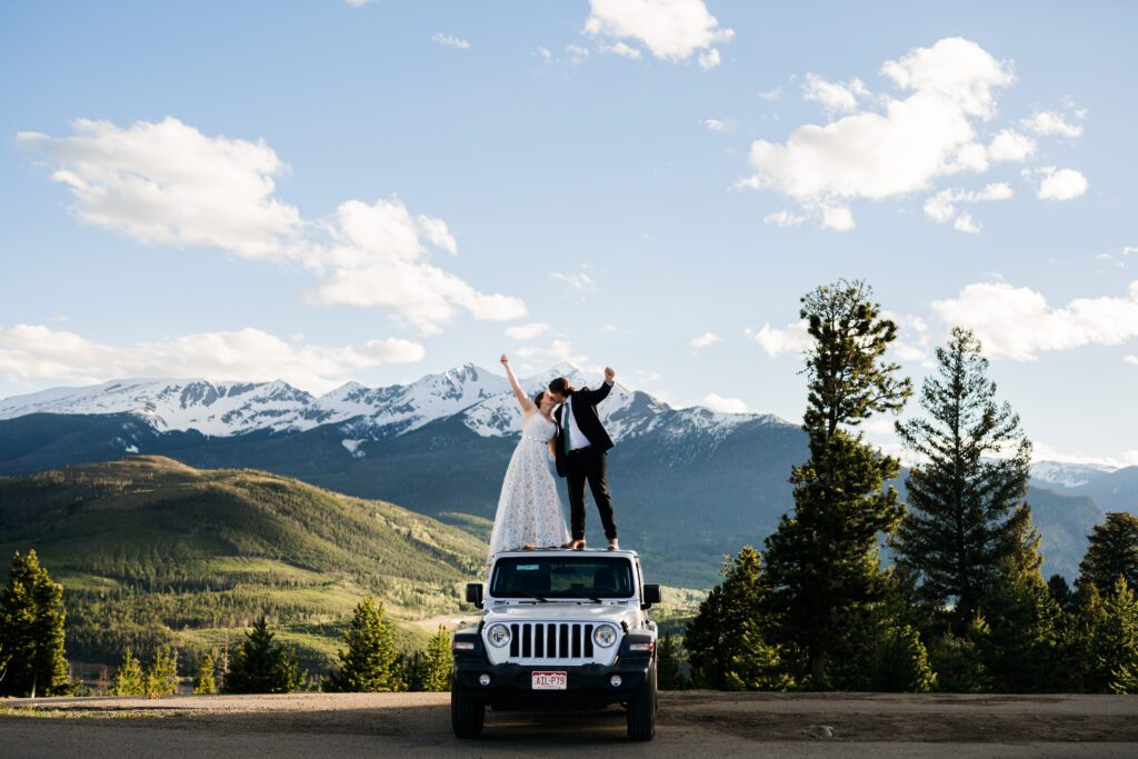 Bride and Groom Standing on top of a jeep kissing and holding hands at Sapphire Point Overlook in Colorado during their Colorado elopement