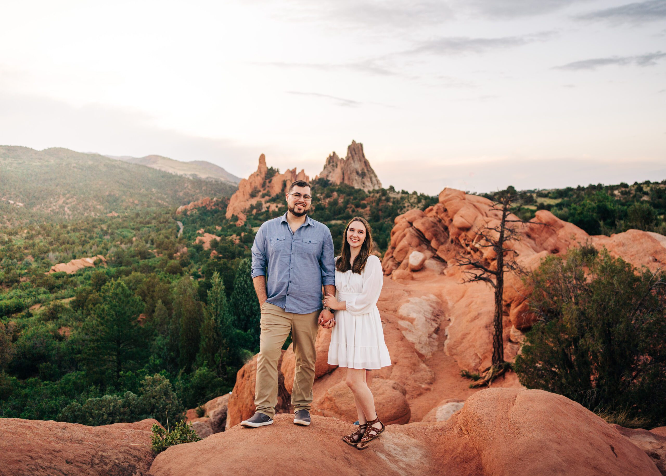 engaged couple standing on top of red rocks at Garden of the Gods in Colorado Springs during their engagement session