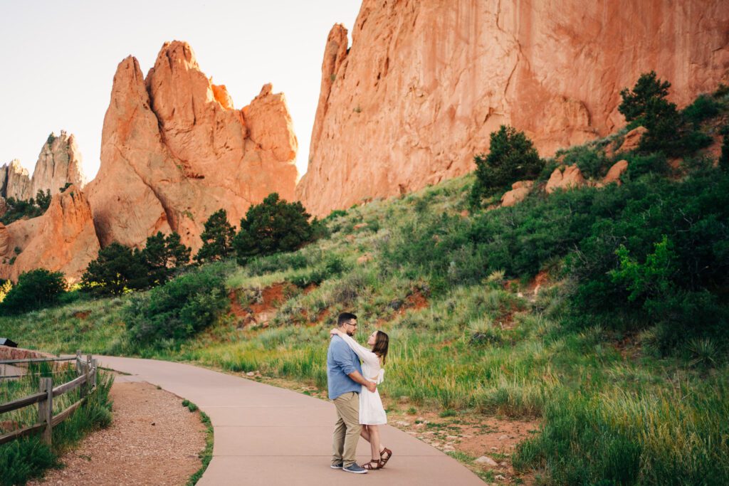 cute engaged couple embracing while walking through Garden of the Gods during their engagement session