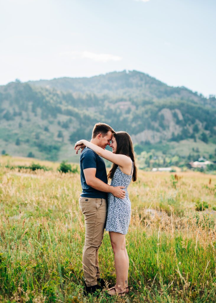 young engaged couple holding eachother with their foreheads touching in a meadow during their boulder engagement photos