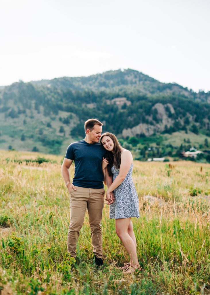 girl holding her boyfriends hand as she leans her head on his shoulder during their sunset boulder colorado engagement session