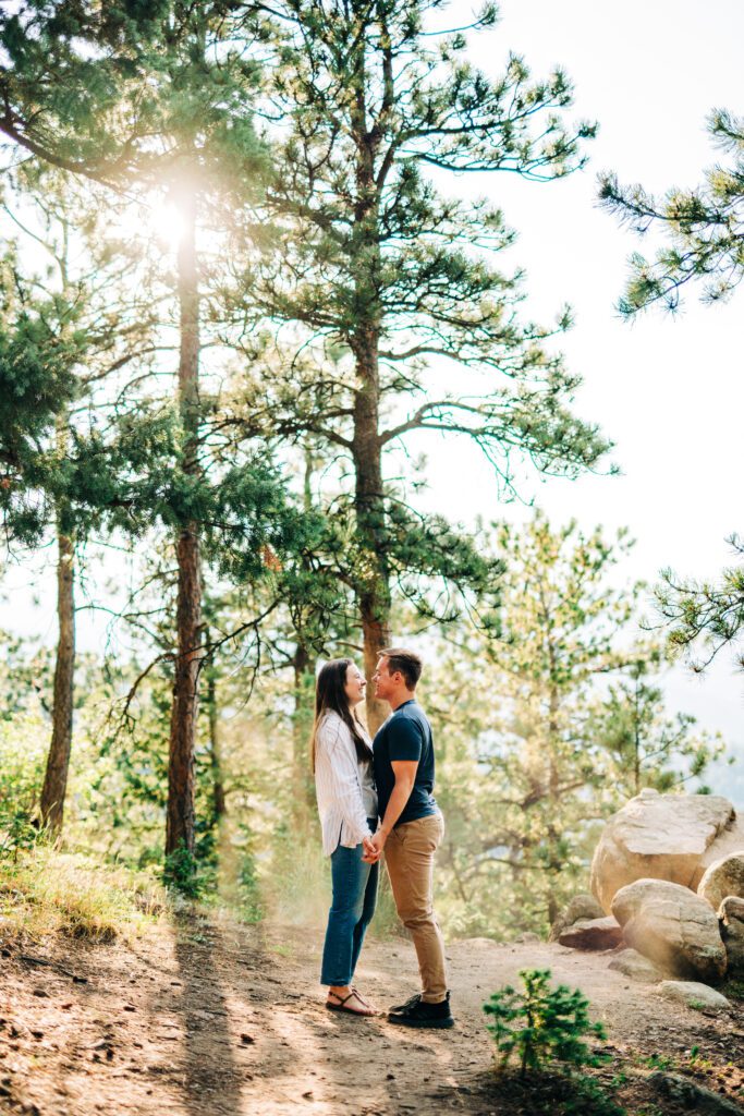 engaged couple holding hands in the forest at lost gulch overlook during their boulder colorado engagement photoshoot