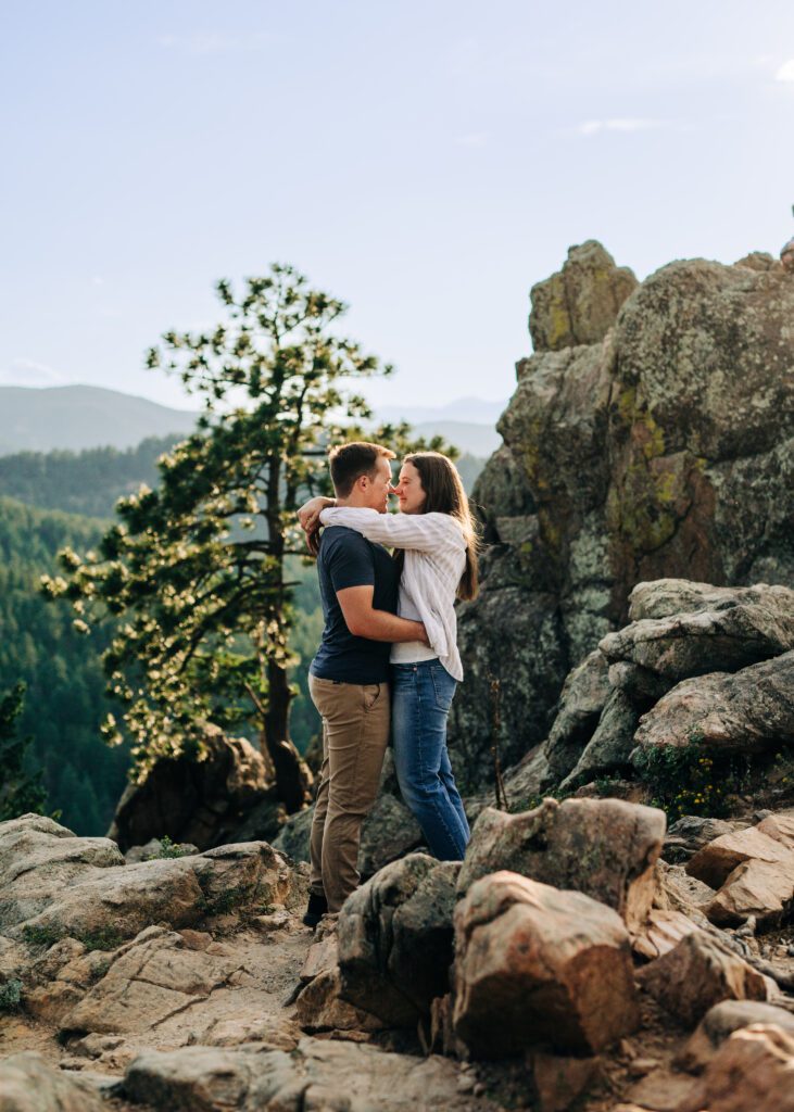 couple standing on cliff hugging eachother at lost gulch overlook during their boulder colorado engagement photoshoot