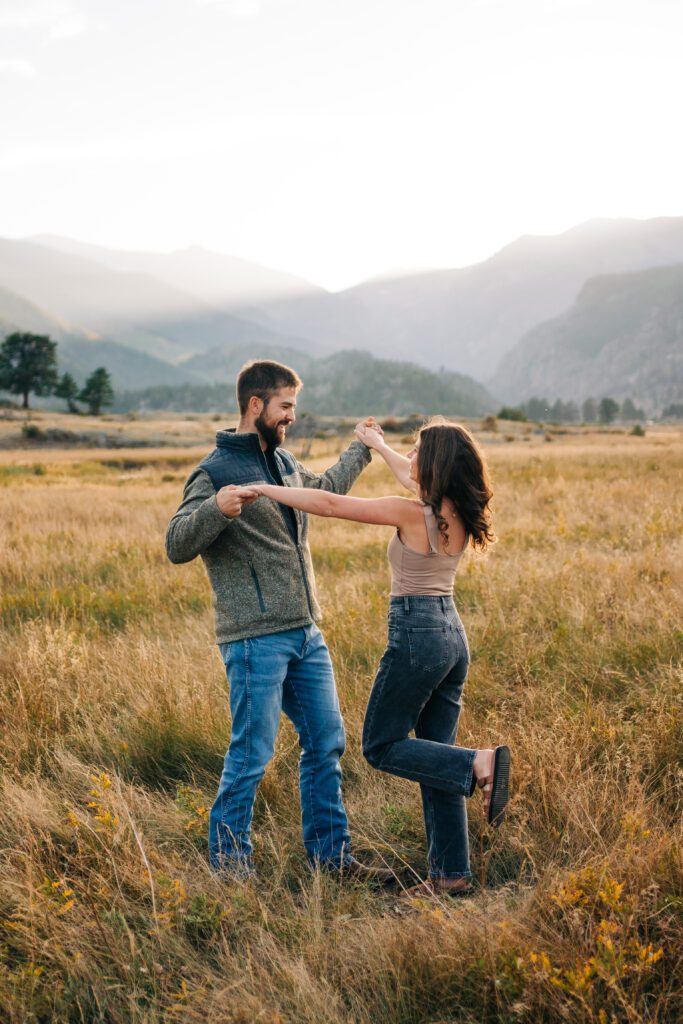 Cute engaged couple dancing in a field at sunset during their rocky mountain national park engagement session