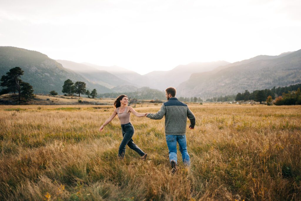 cute engaged couple running around Moraine Park in Rocky Mountain National Park after just getting engaged