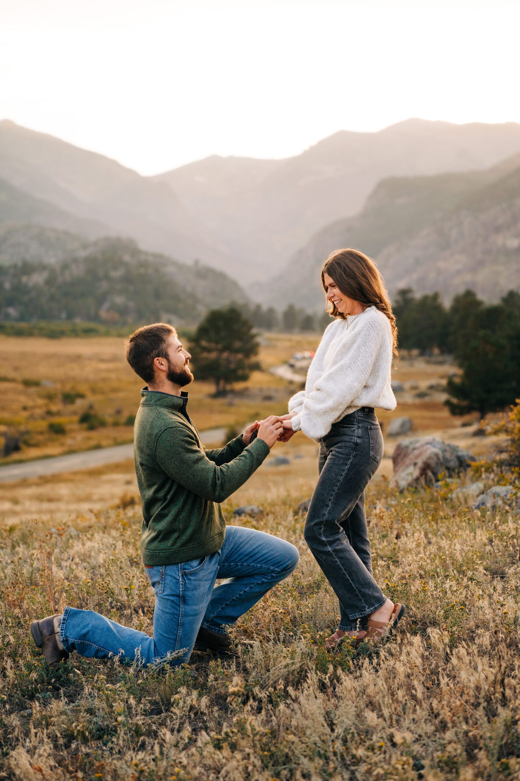 Closeup of boyfriend down on one knee proposing to his girlfriend at Moraine Park in Rocky Mountain National Park in Colorado during sunset