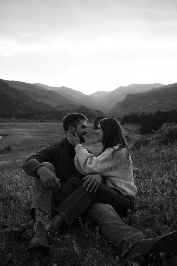 girlfriend and boyfriend sitting down together while she holds his face after he proposed in Moraine Park at Rocky Mountain National Park in Colorado