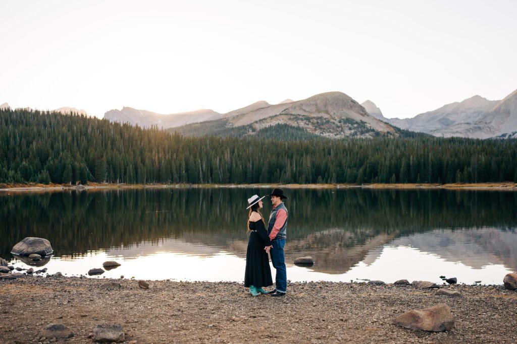 Western inspired engagement session at Brainard Lake Recreation Area - Couple holding hands in front of the mountains and lake during their engagement session