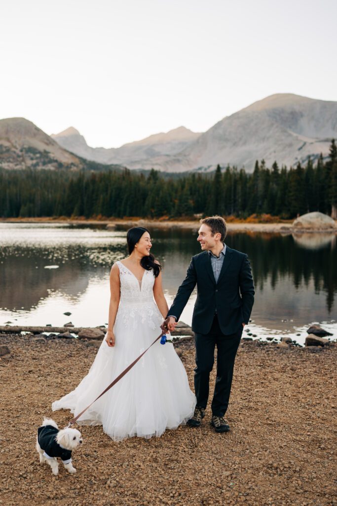 bride and groom walking their dog along the lakeshore during their brainard lake elopement