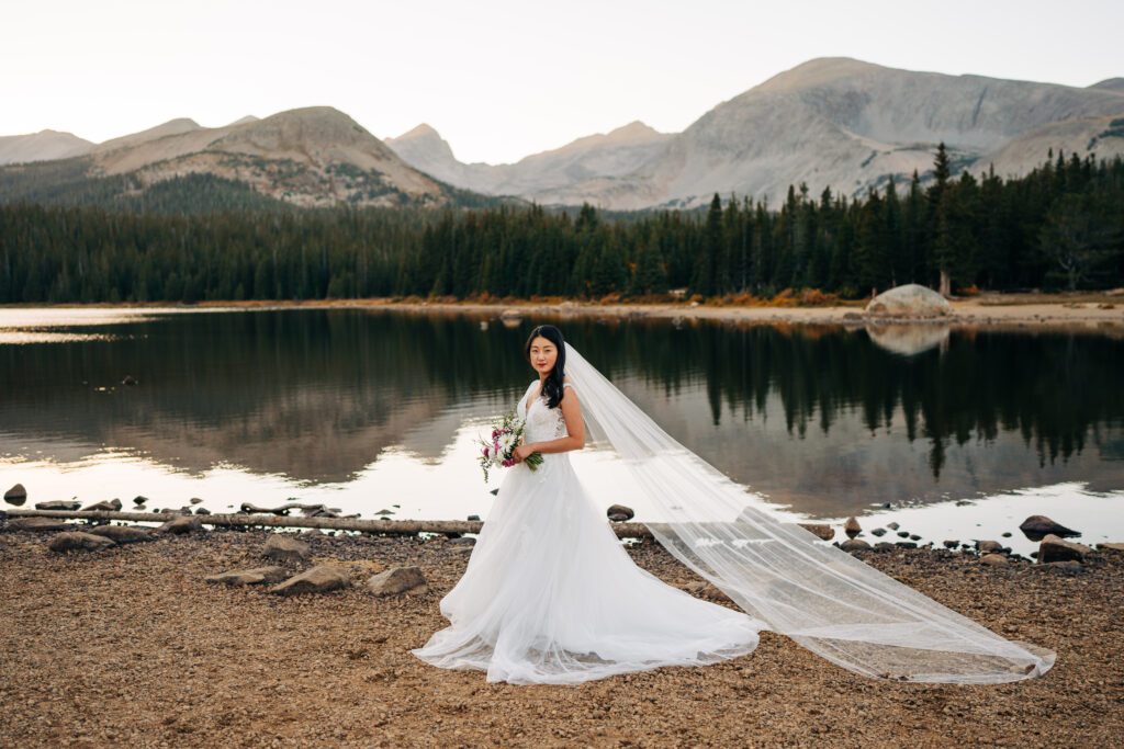 sunset portrait of bride with the mountains and lake in the background during her brainard lake elopement near boulder colorado