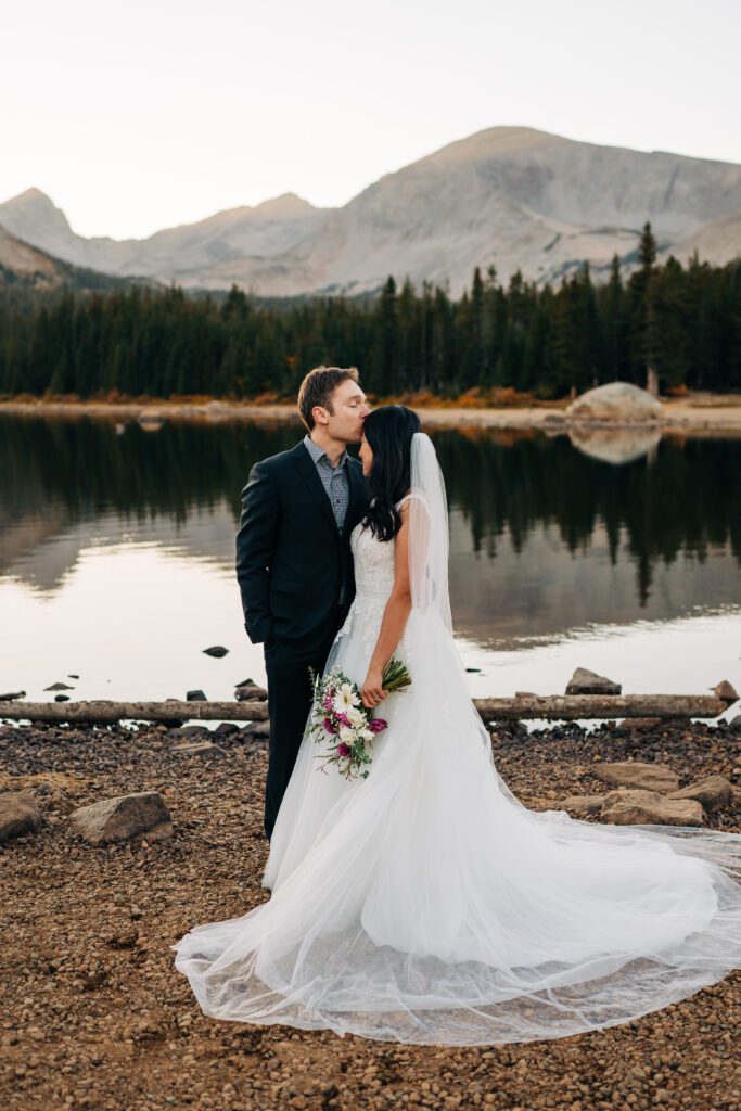 groom and bride snuggled up while he kisses her on the forehead during their sunset brainard lake elopement near boulder colorado