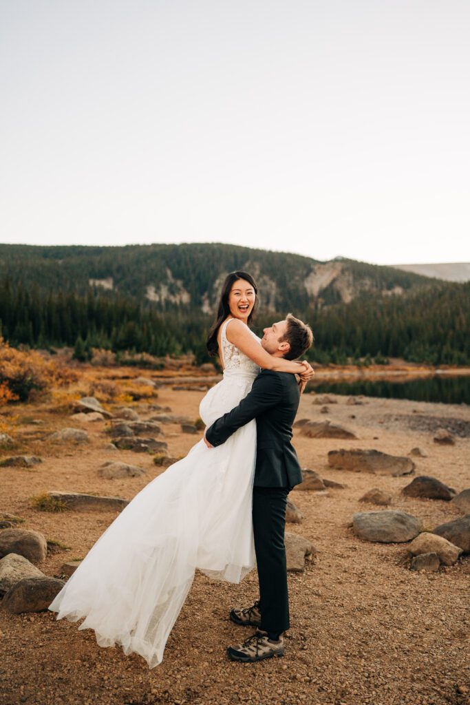 Groom lifting up bride on the lakeshore during their brainard lake elooement near boulder colorado