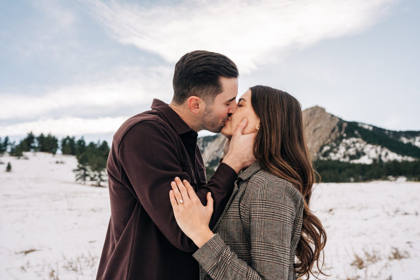 Boyfriend grabbing his girlfriends face and kissing her after they got engaged at Chautauqua Park in Boulder, Colorado during their winter engagement session