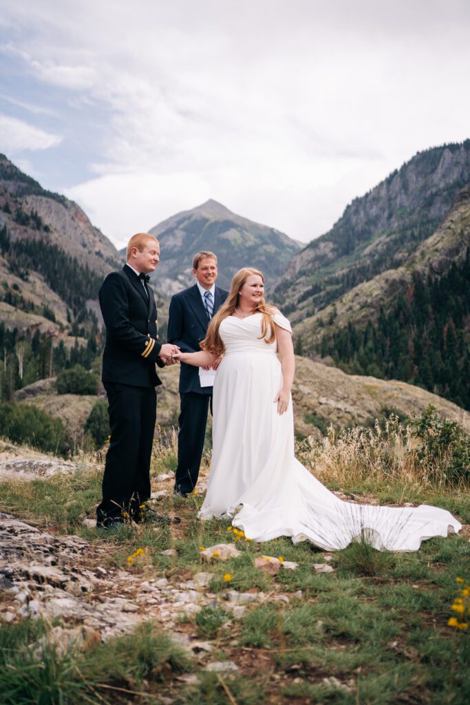 bride holding grooms hand while listening to her sister say a few words during her ouray elopement ceremony in colorado