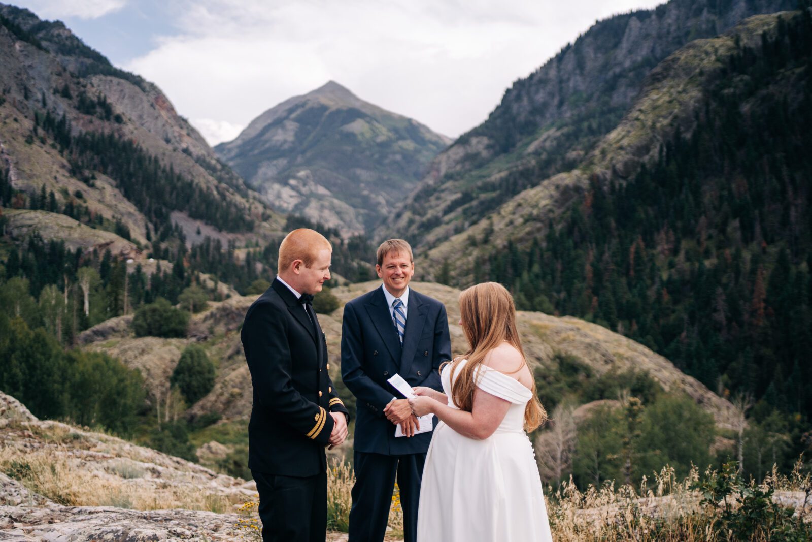 bride reading her vows to the groom with mountainscape in the background during their ouray elopement in colorado