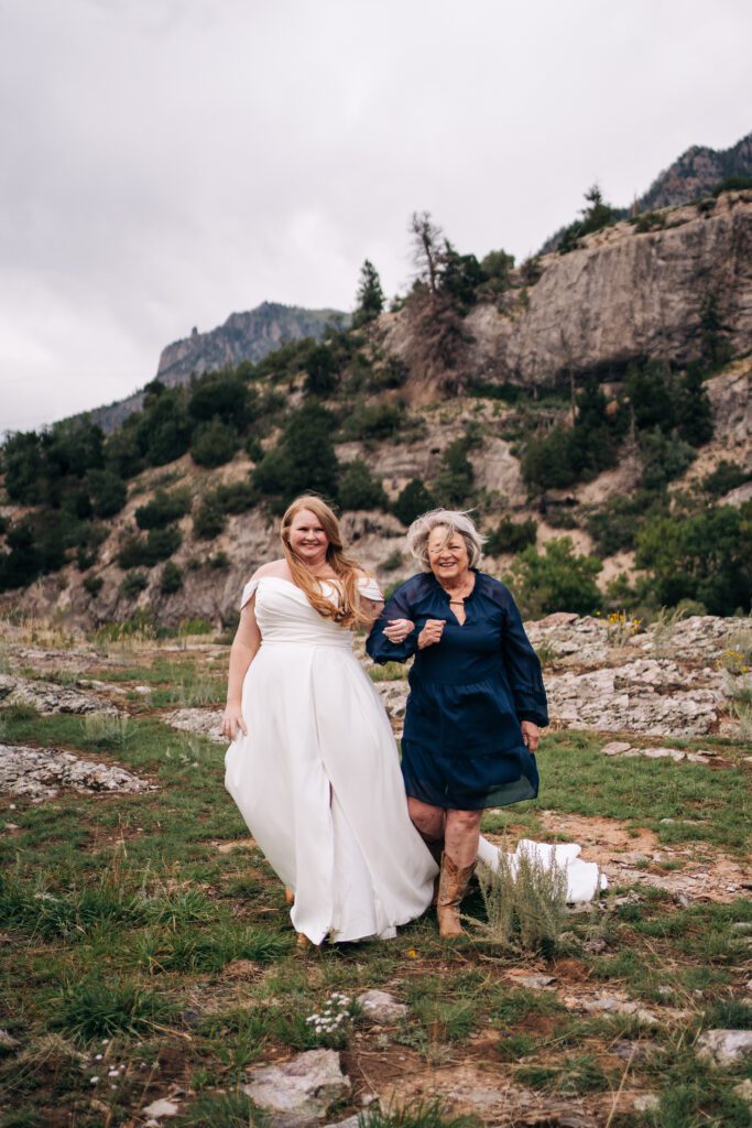 Bride walking down the aisle holding her moms arm in the mountains during their ouray elopement in colorado