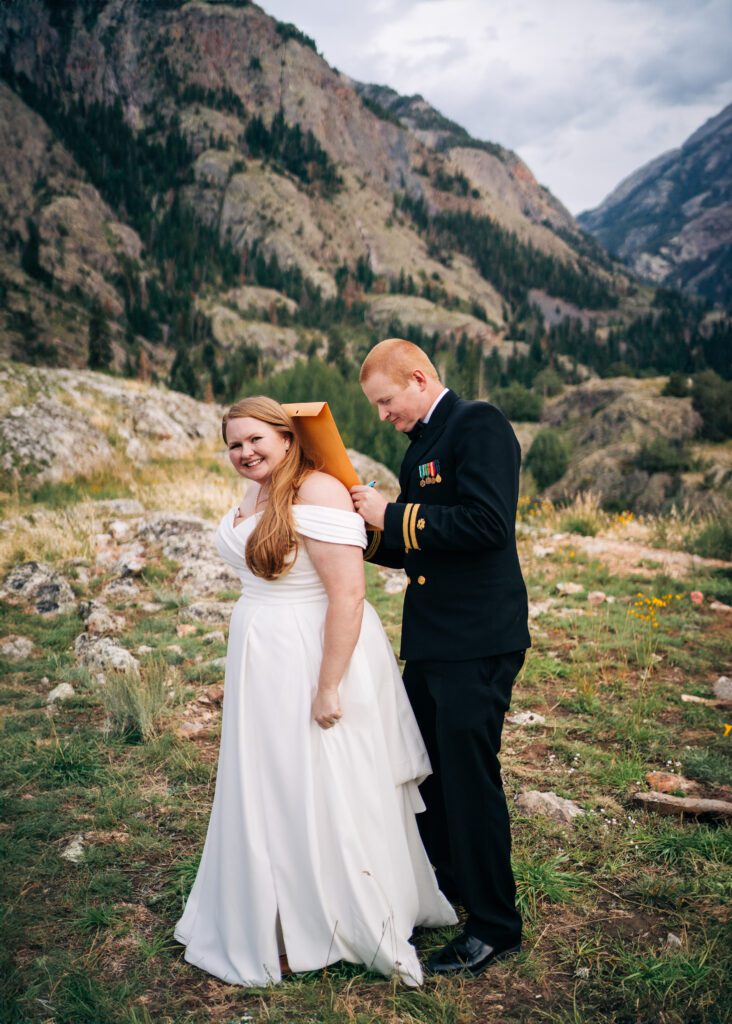 groom signing their marriage license on brides back in front of a mountain during their ouray elopement