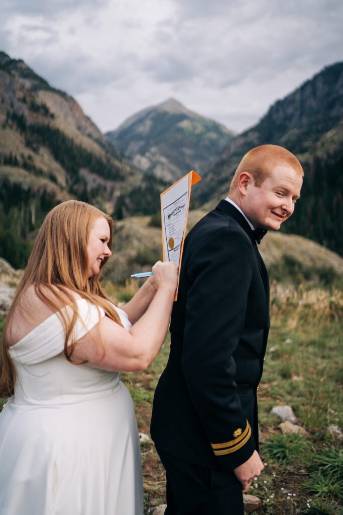 bride signing marriage license on grooms back during their ouray elopement in colorado