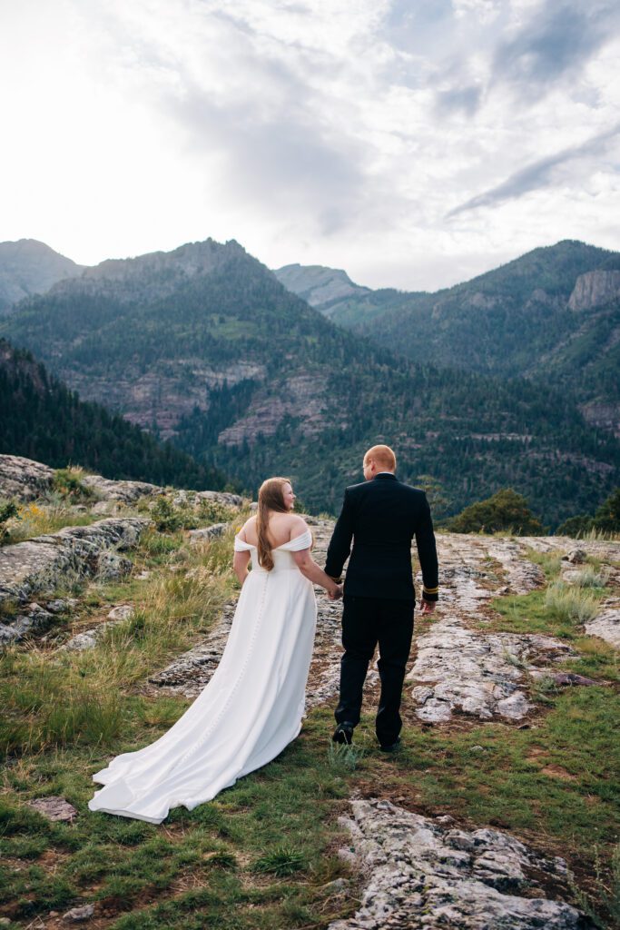 bride and groom holding hands walking away from the camera towards the mountains during their ouray elopmenet in colorado