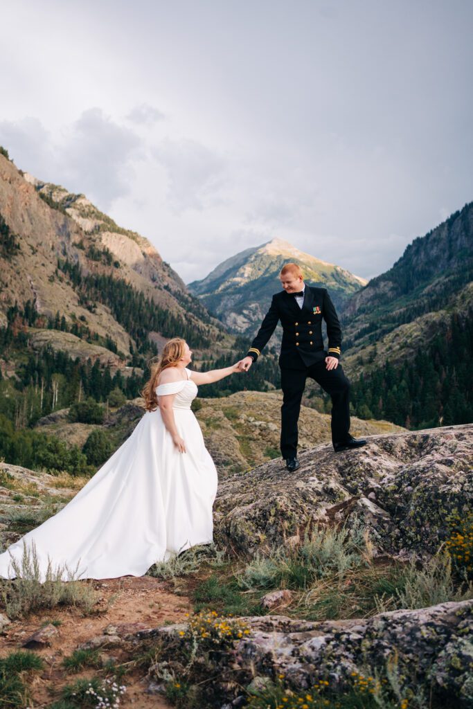 Groom helping bride up a rock during their Ouray elopement in Colorado