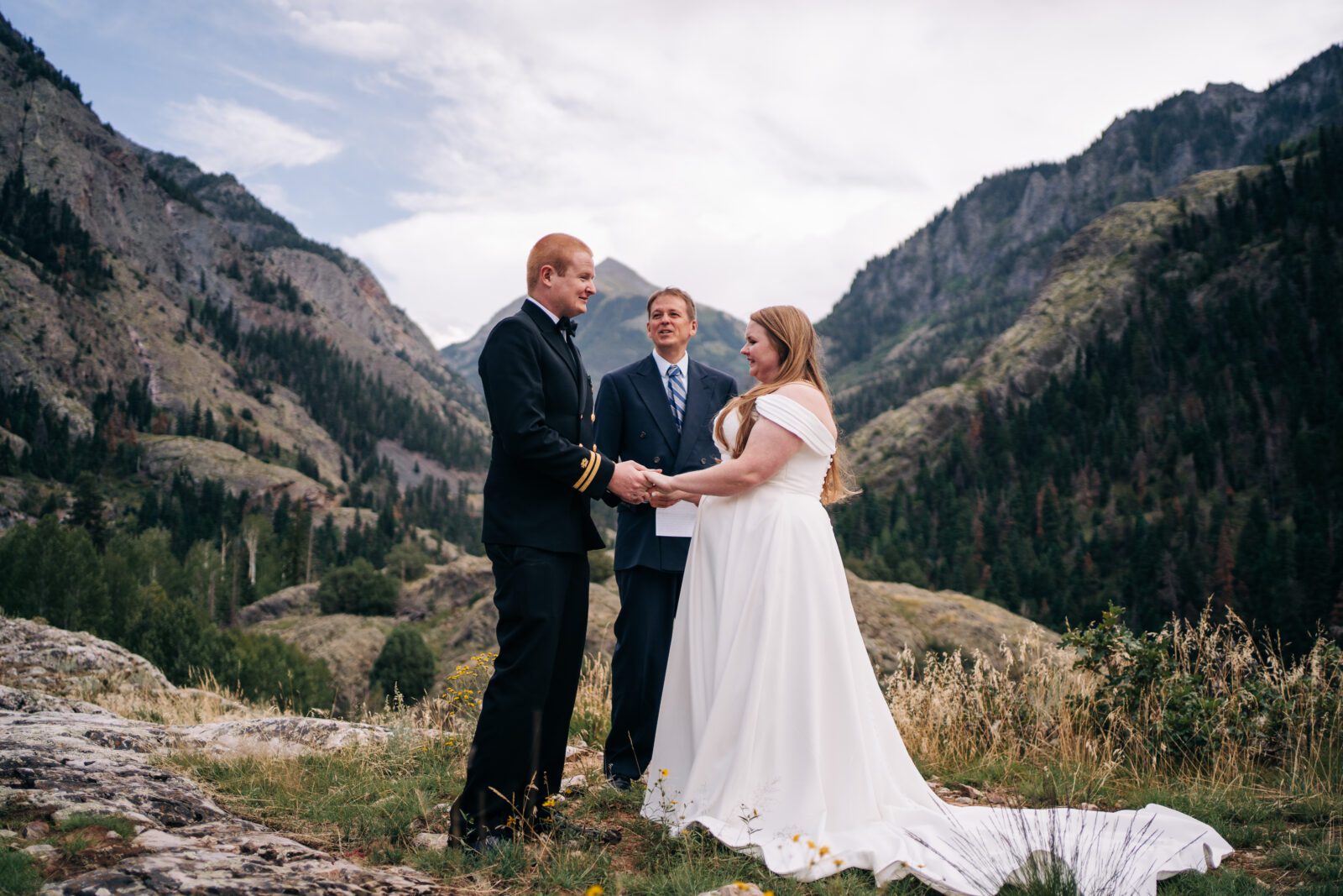 Bride and groom holding hands in front of a mountain during their ouray elopement in colorado