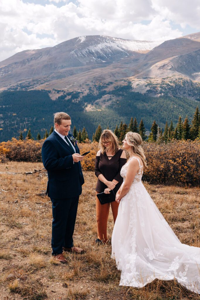 Groom reading his vow while everyone listens on top of a mountain in Colorado during their Breckenridge elopement