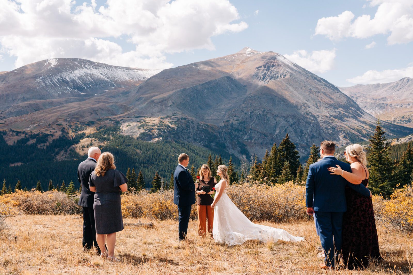 Bride and groom holding hands during their wedding ceremony on top of a mountain in Colorado during their Breckenridge elopement