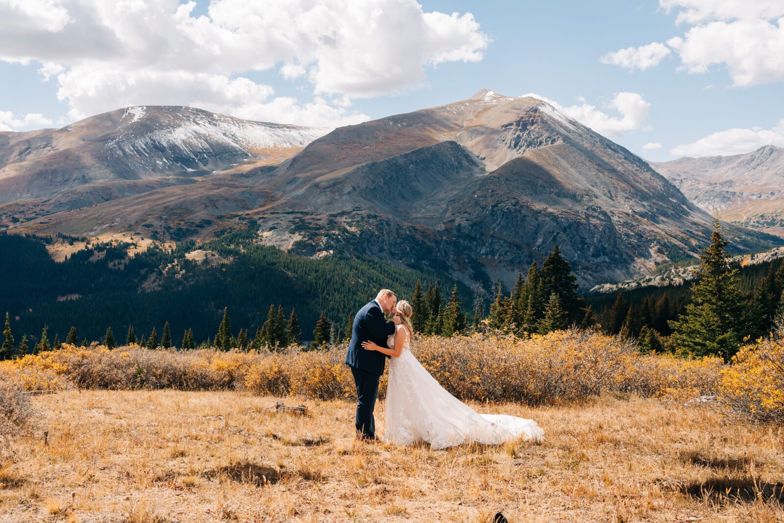 Groom and bride sharing their first kiss on top of a mountain after their Breckenridge elopement ceremony