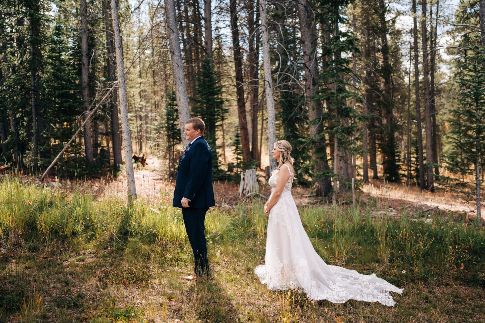 Bride standing behind groom about to tap his shoulder for their first look during their Breckenridge elopement