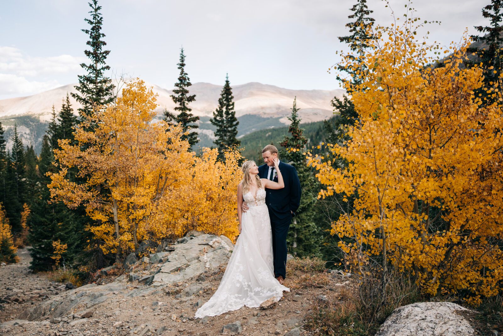 Bride and groom holding each other and kissing in the forest in the mountains of Colorado during their Breckenridge elopement