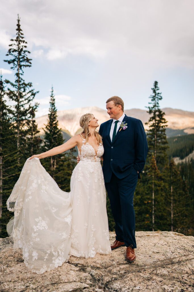 Bride and groom snuggled up together smiling at eachother while the bride tosses her dress up in the air during their Breckenridge elopement photos