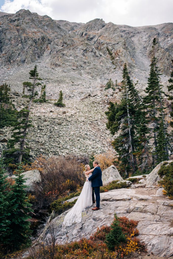 Bride and groom standing on a rock in the mountains during their Breckenridge elopement