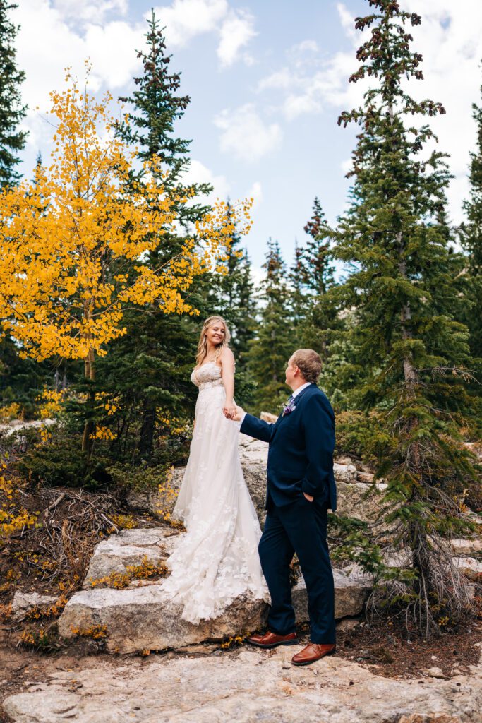 Bride climbing up the steps while holding the grooms hands in the mountains of Colorado during their Breckenridge elopement