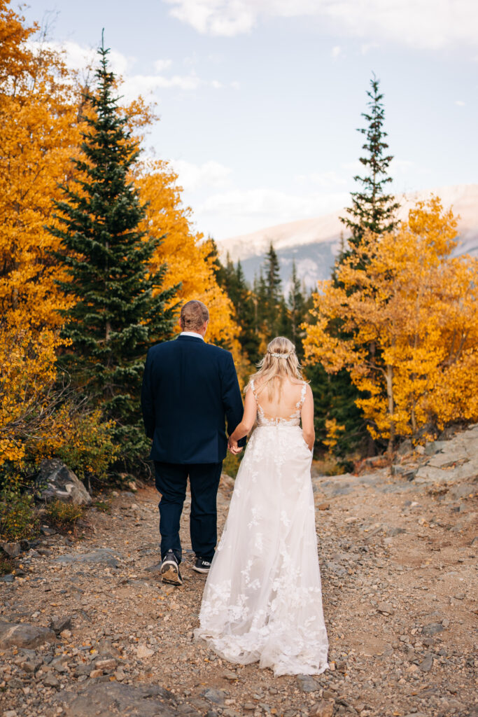 Bride and groom holding hands and walking down the hiking trail in the Colorado mountains during their Breckenridge elopement photos