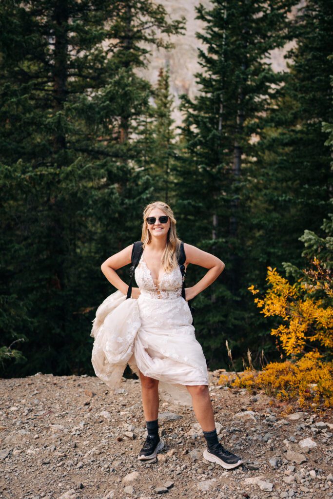 Portrait of bride standing in the middle of the Colorado mountains with her hiking gear on during her Breckenridge elopement photos