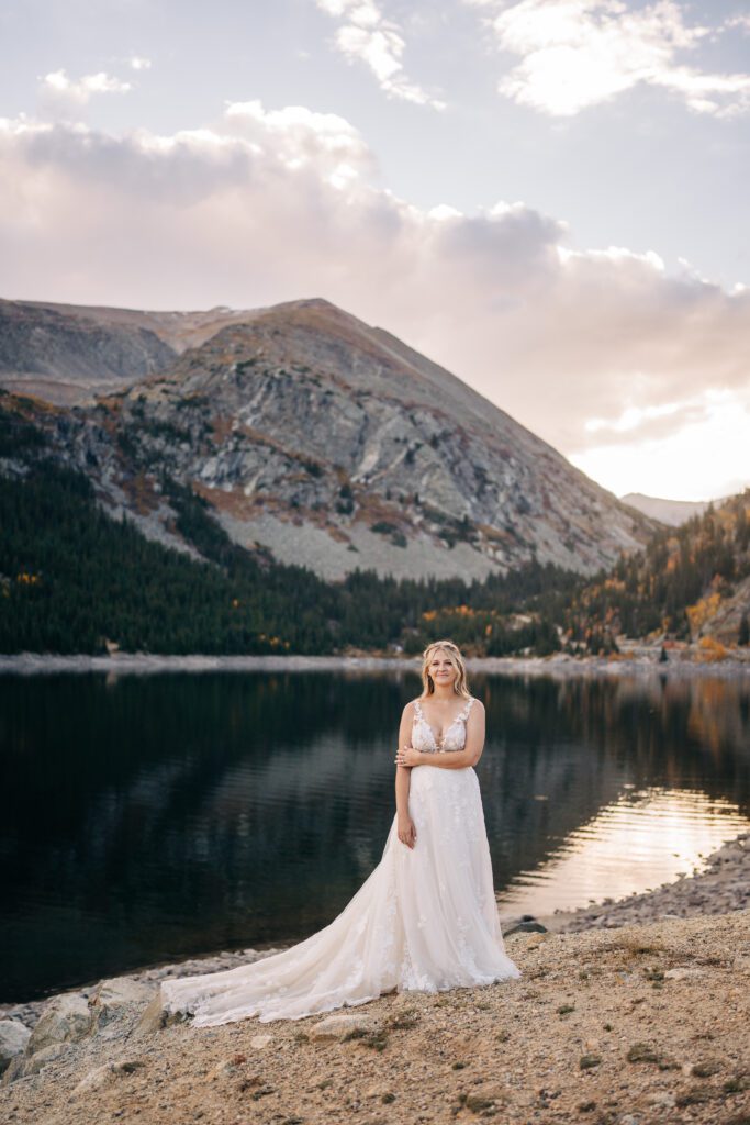 Solo portrait of bride standing in front of an alpine lake in Colorado during her Breckenridge elopement