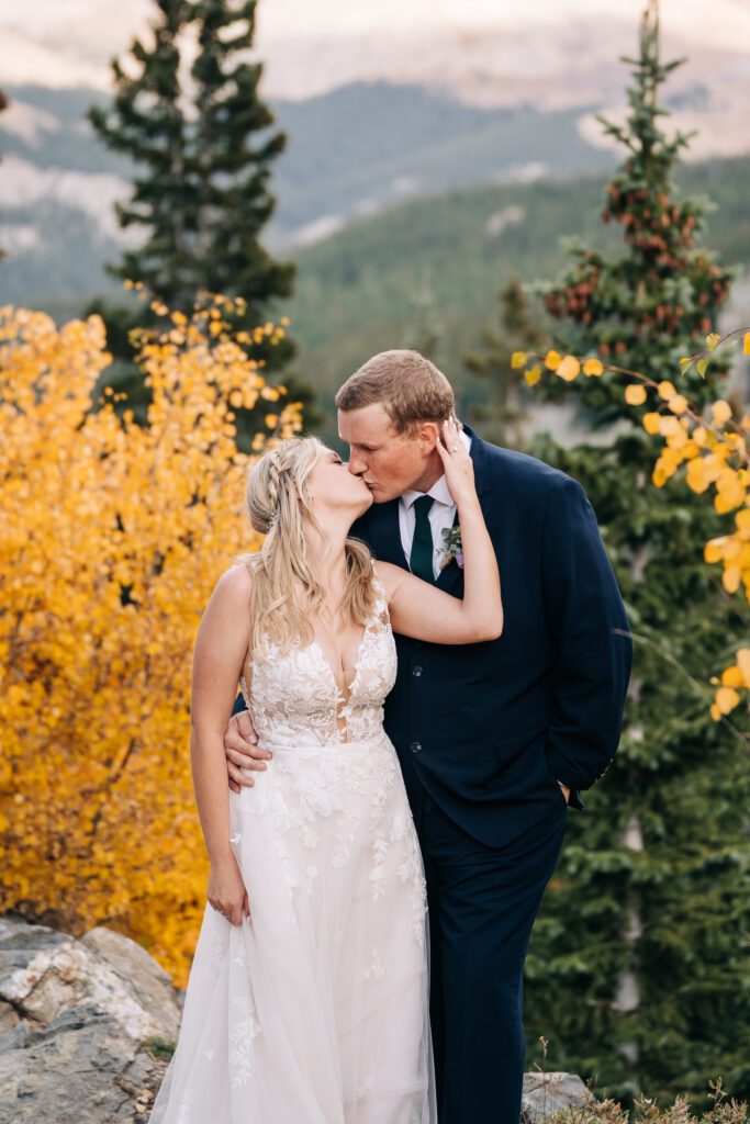 Bride and Groom kissing and holding each other in the forest in the Colorado mountains during their Breckenridge elopement