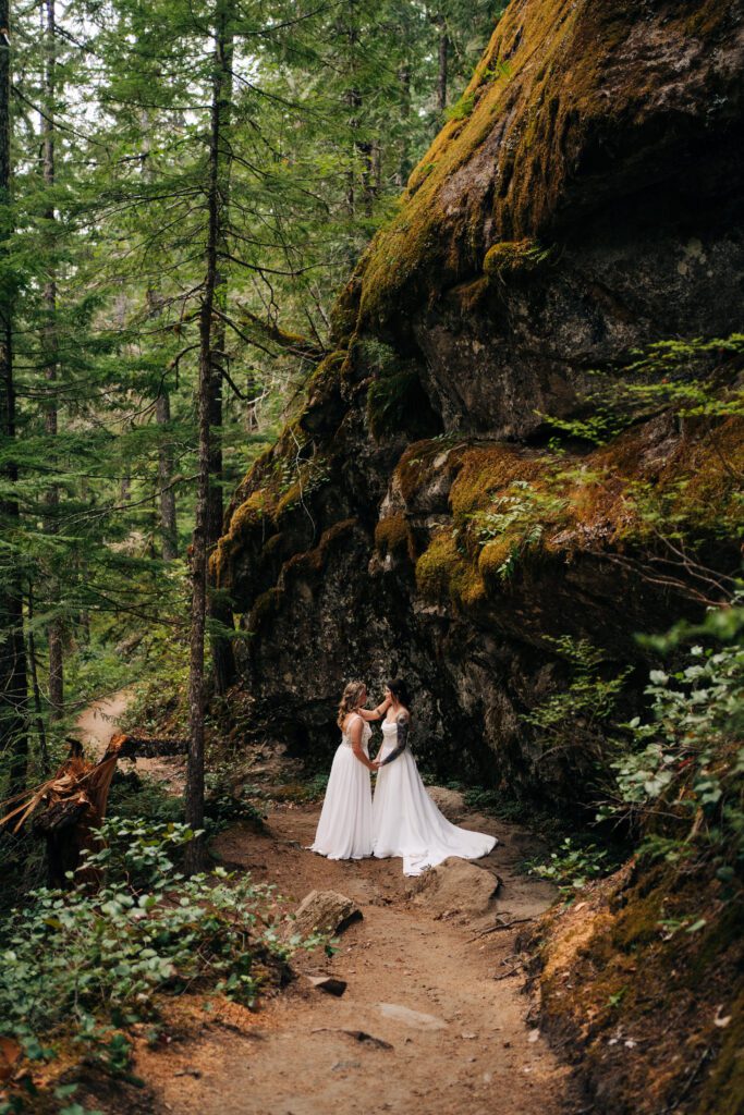 wife and wife holding hands in the forest after their ceremony during their washington elopement in mt rainier national park