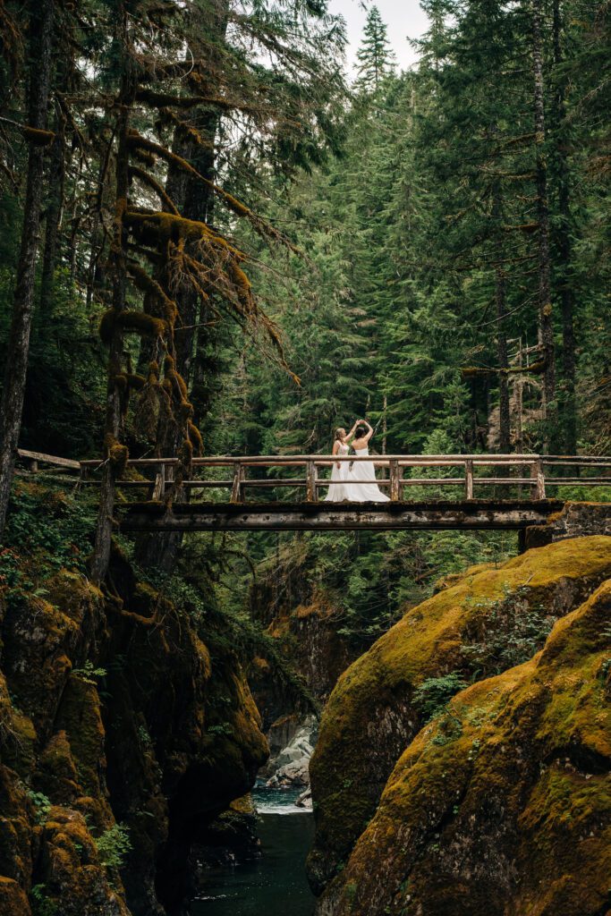 wife twirling her wife on a bridge during their washington elopement in mt rainier national park