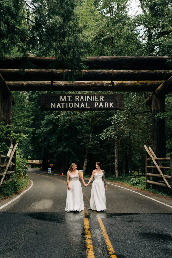 wives holding hands walking through mt rainier national park during their washington elopement