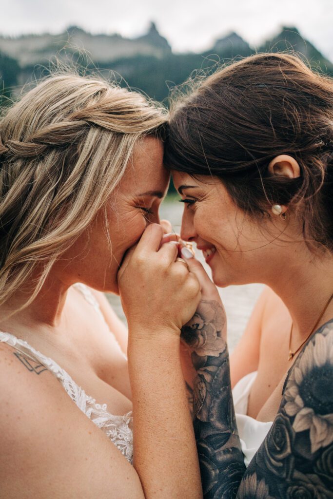 wife kissing her wives hands during their washington elopement in mt rainier national park