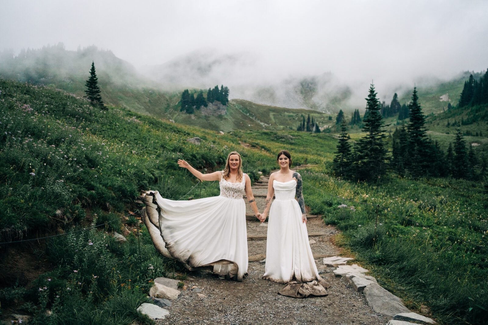 bride tossing her dress up while her wife watches her during their washington elopement in mt rainier national park