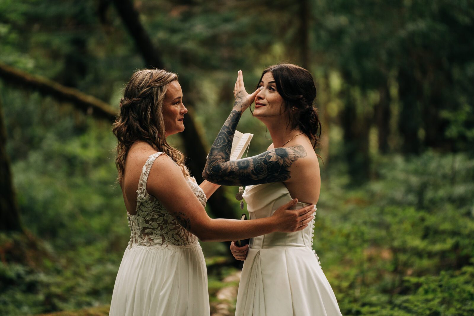 bride wiping her wife's tears off her cheek during their wedding ceremony in mt rainier national park during their washington elopement 