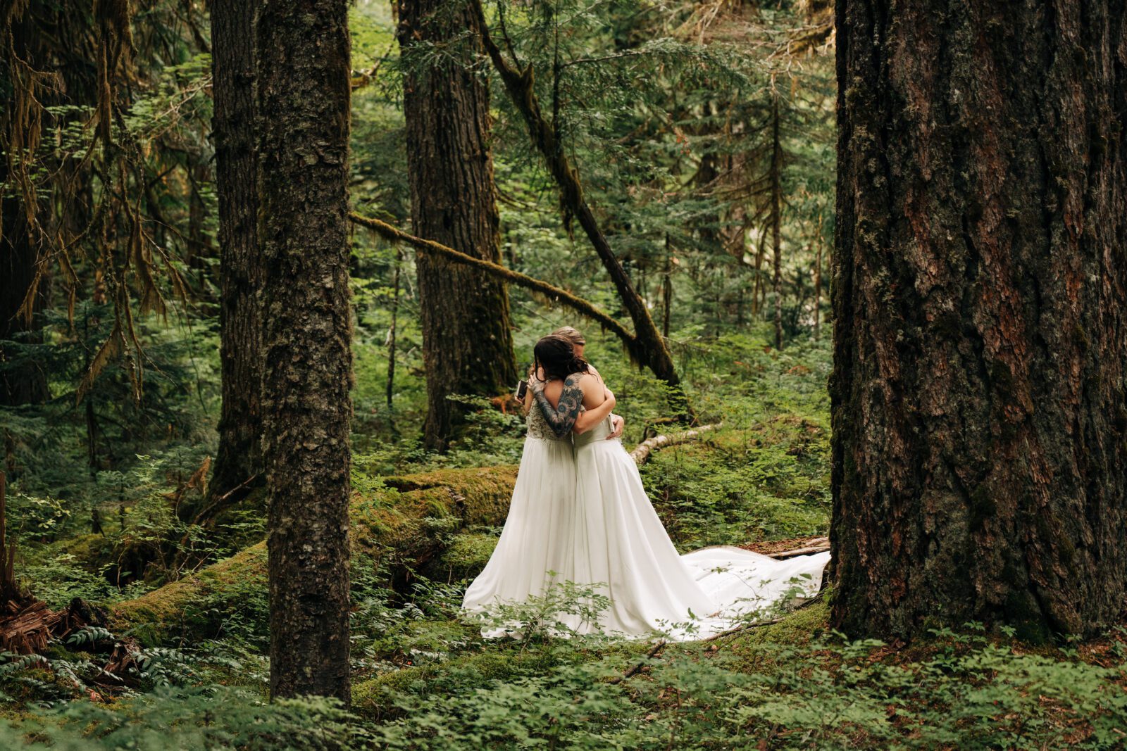 wifes hugging during their elopement ceremony in the forest in mt rainier during their washington elopement