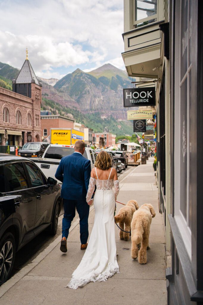 bride and groom walking down the street with their two dogs during their Telluride elopement