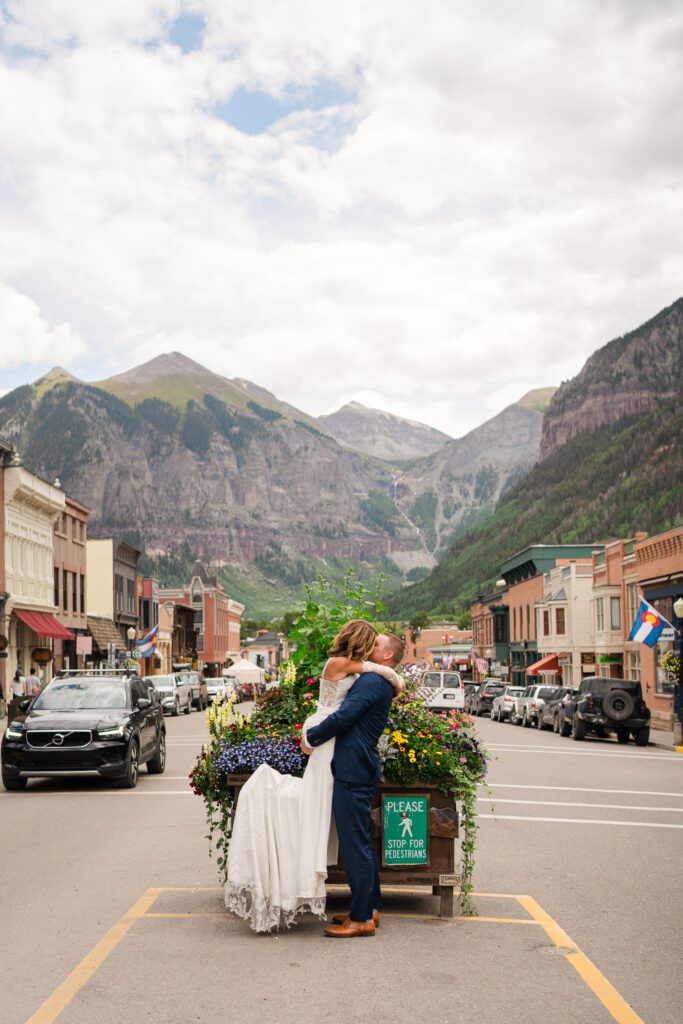 Bride and groom kissing as he lifts her up in the middle of the street in downtown Telluride during their Telluride elopement day